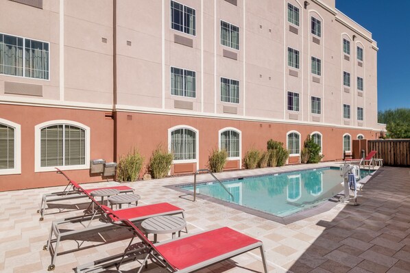 Um hotel com piscina, espreguiçadeiras e um terraço coberto.