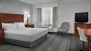 A hotel room with a large bed, a desk, a chair, a television, a lamp, and a window with curtains. - TownePlace Suites Tucson Williams Centre (Tucson)