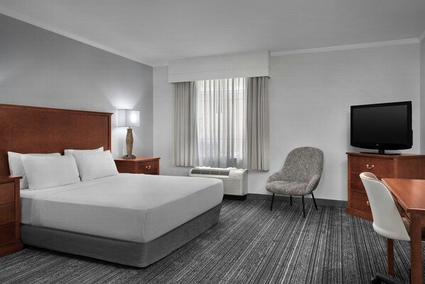 A hotel room with a large bed, a desk, a chair, a television, a lamp, and a window with curtains. - TownePlace Suites Tucson Williams Centre (Tucson)