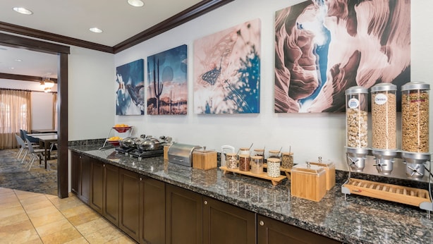 A hotel kitchen with granite countertops, a buffet setup, and three large wall art pieces. - TownePlace Suites Tucson Williams Centre (Tucson)