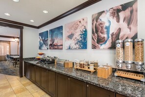 A hotel kitchen with granite countertops, a buffet setup, and three large wall art pieces. - TownePlace Suites Tucson Williams Centre (Tucson)