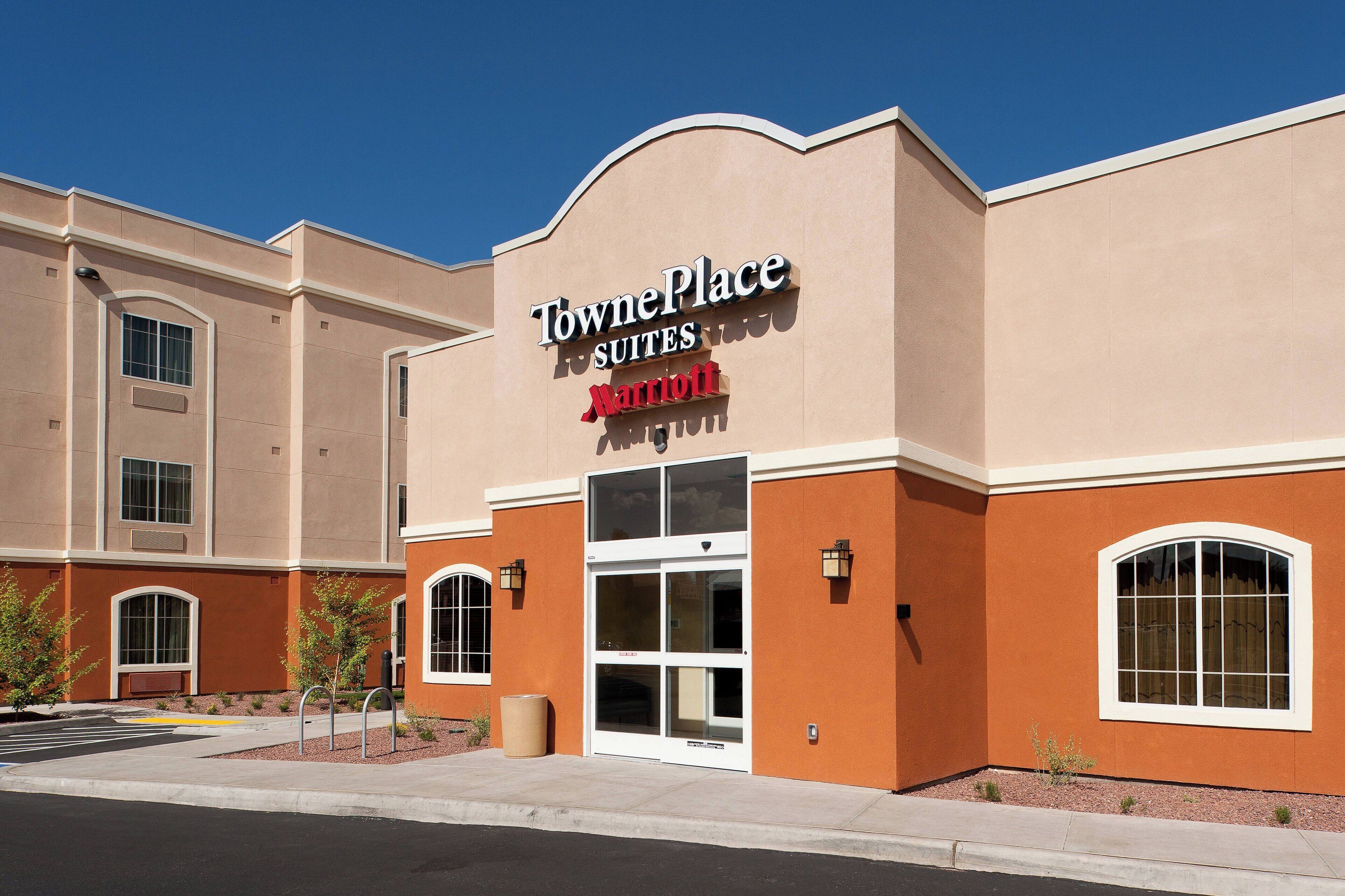 A TownePlace Suites Marriott hotel with a beige facade, large windows, and a clear sky.