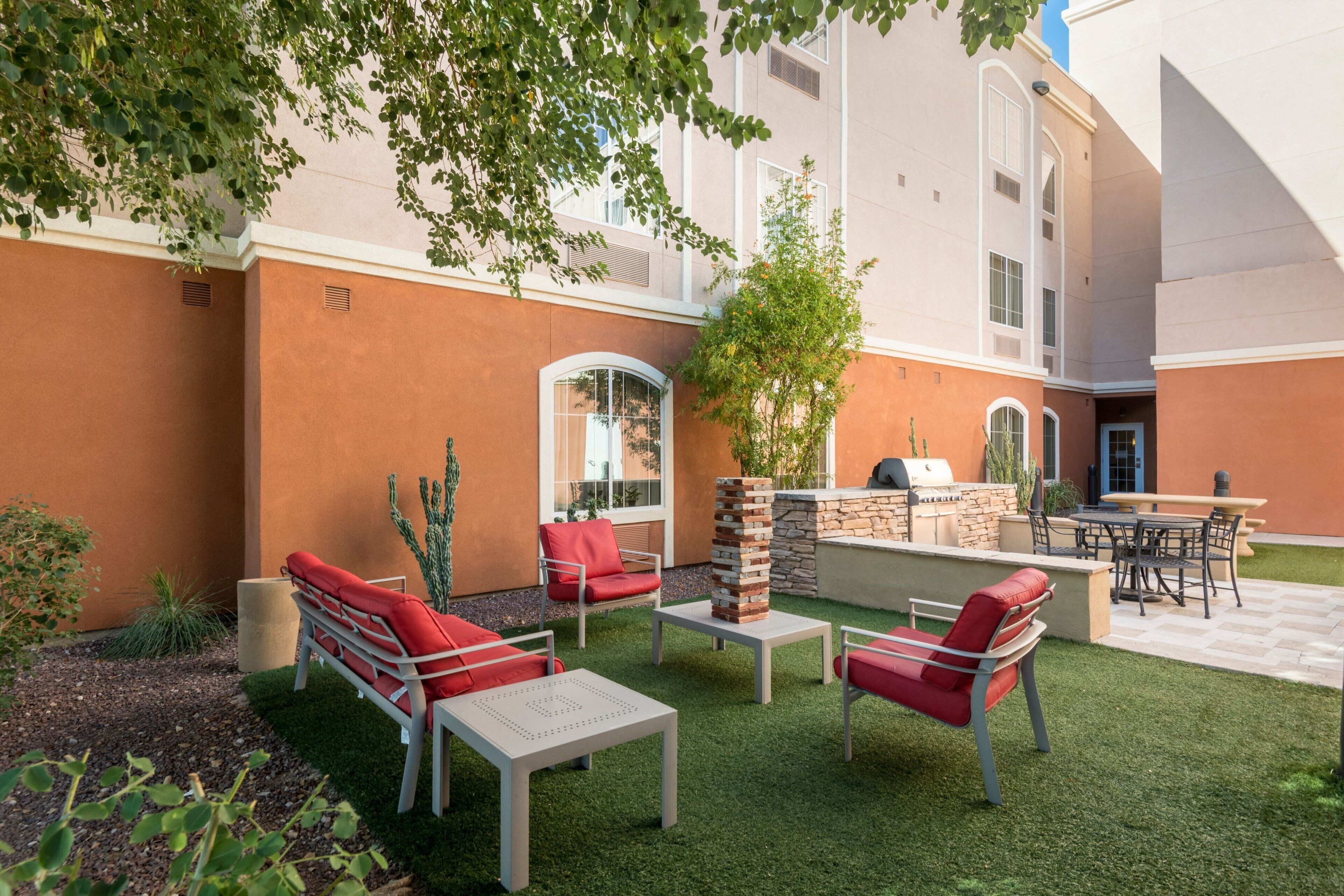 An outdoor patio area with a barbecue grill, seating arrangements, and a stone fireplace.