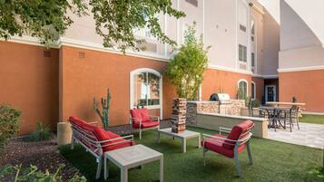 An outdoor patio area with a barbecue grill, seating arrangements, and a stone fireplace.