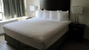 A hotel room with a large bed, two bedside lamps, a window with curtains, and a nightstand.