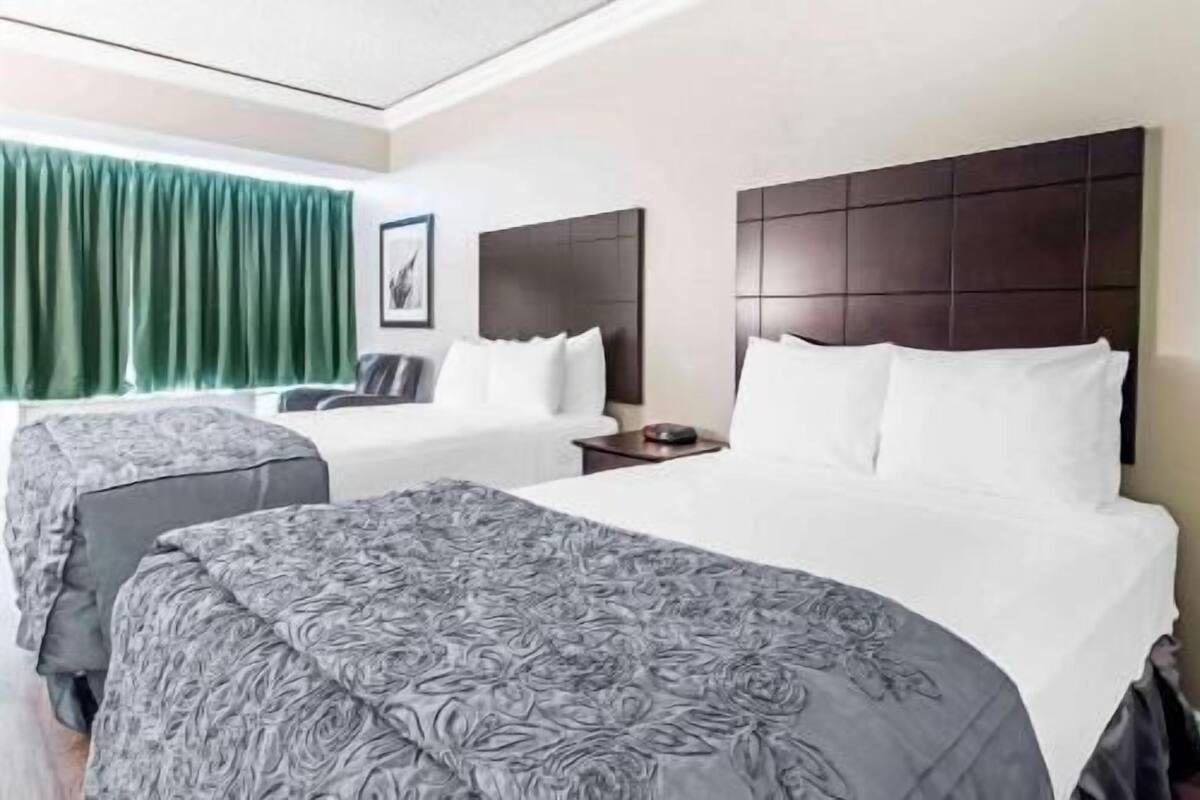 Une chambre d’hôtel avec un grand lit, un lit plus petit, un bureau et une chaise.