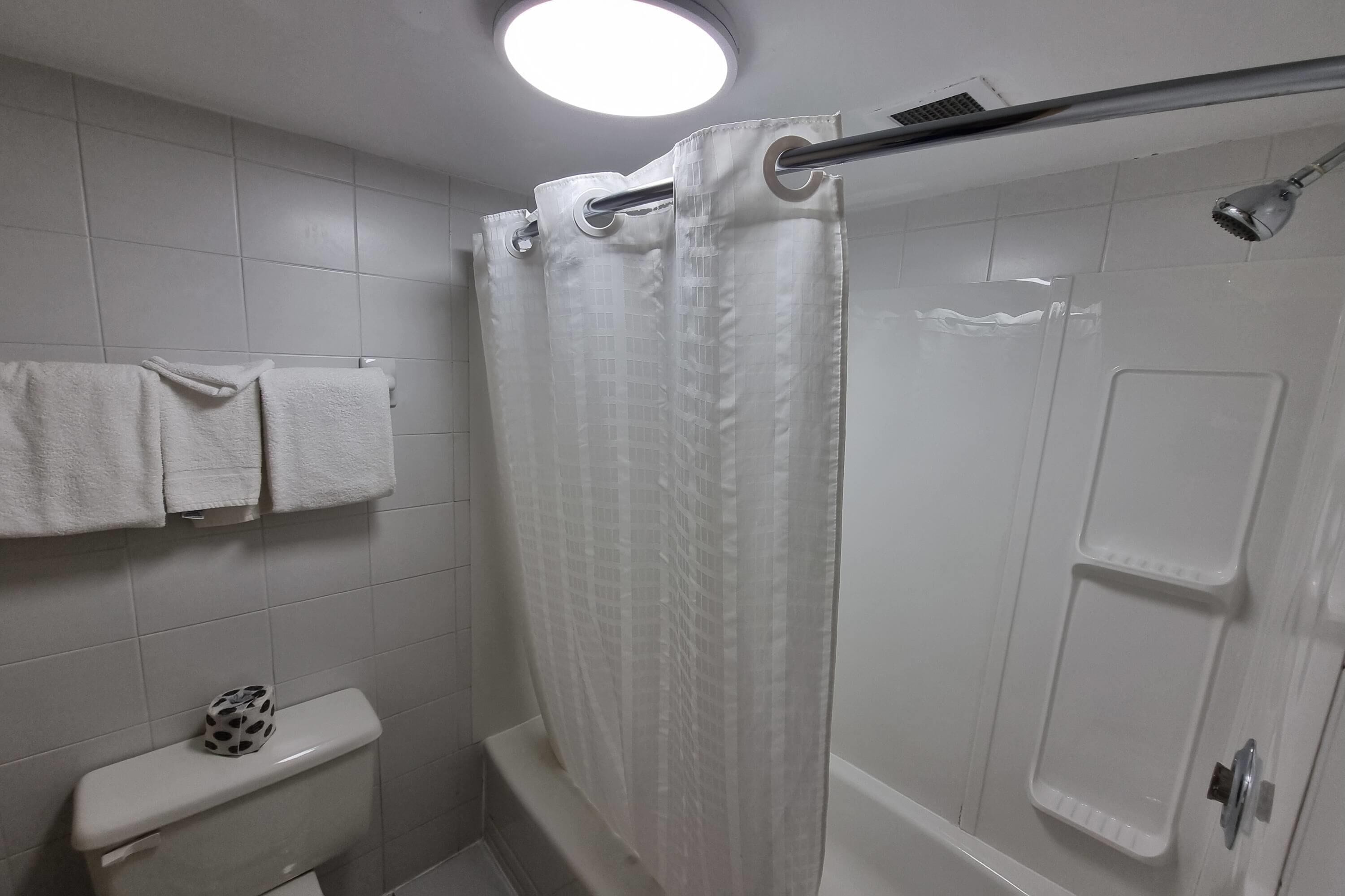 A bathroom with a shower curtain, a toilet, and a towel rack.