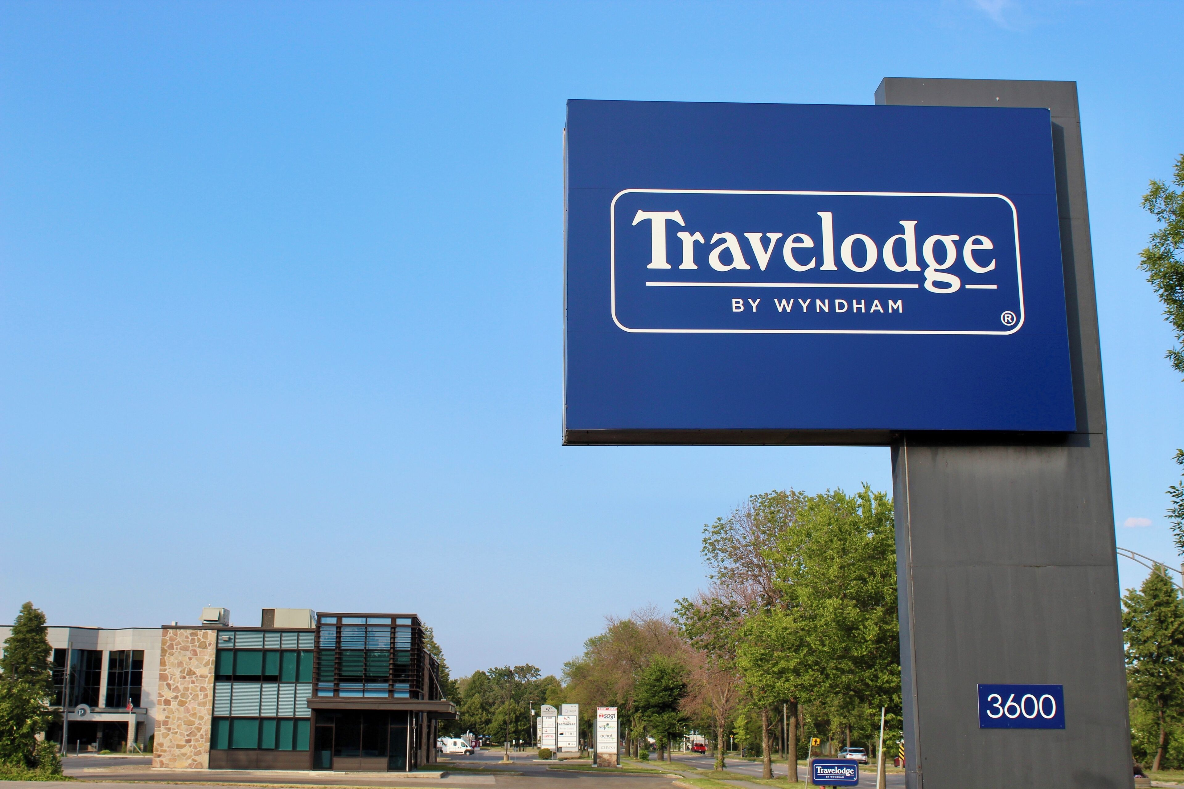 A Travelodge sign with a modern building in the background.
