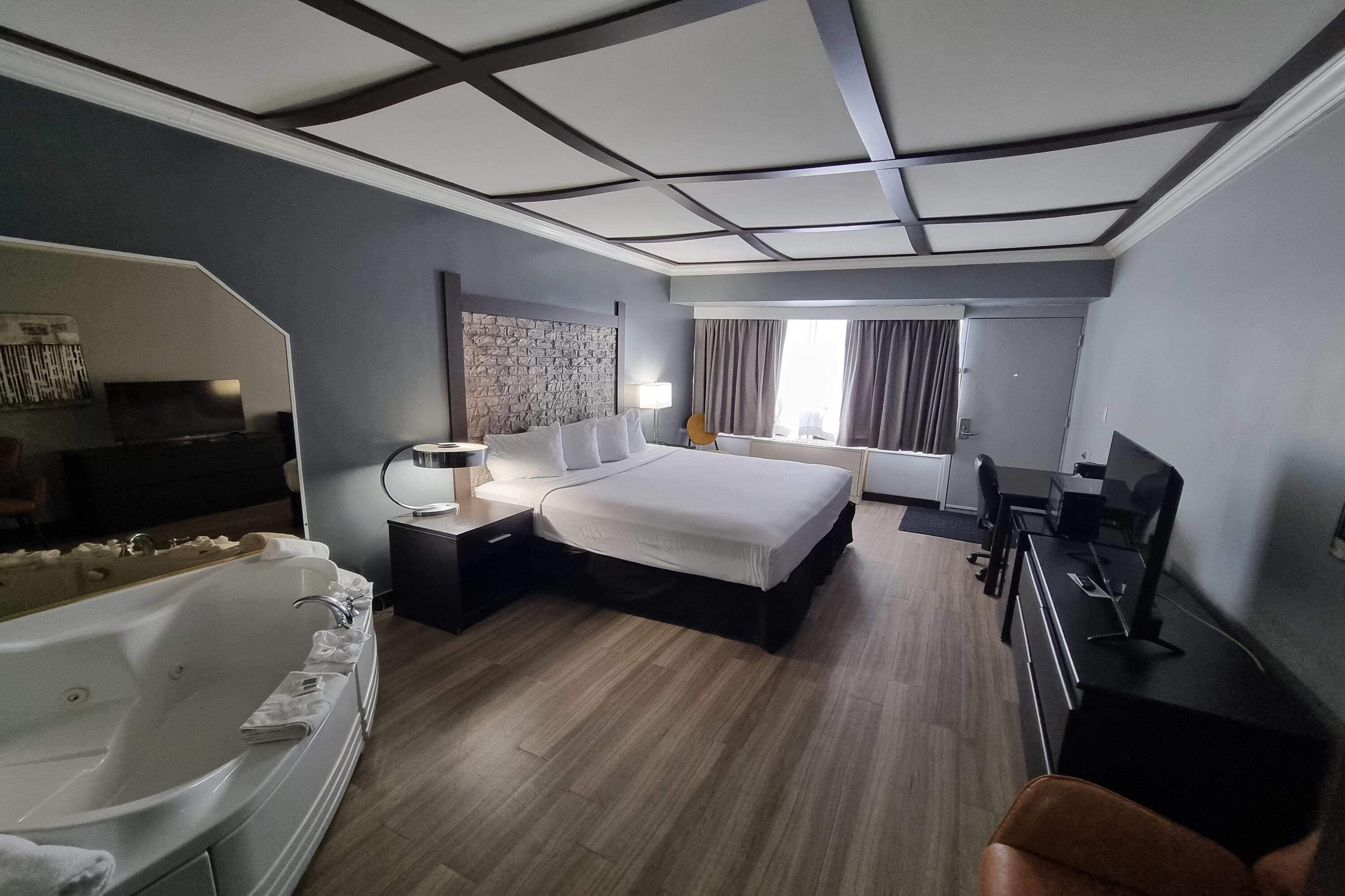 Et hotelv ærelse med en stor seng, et siddeområde med skrivebord og stol, et badekar og et fjernsyn.