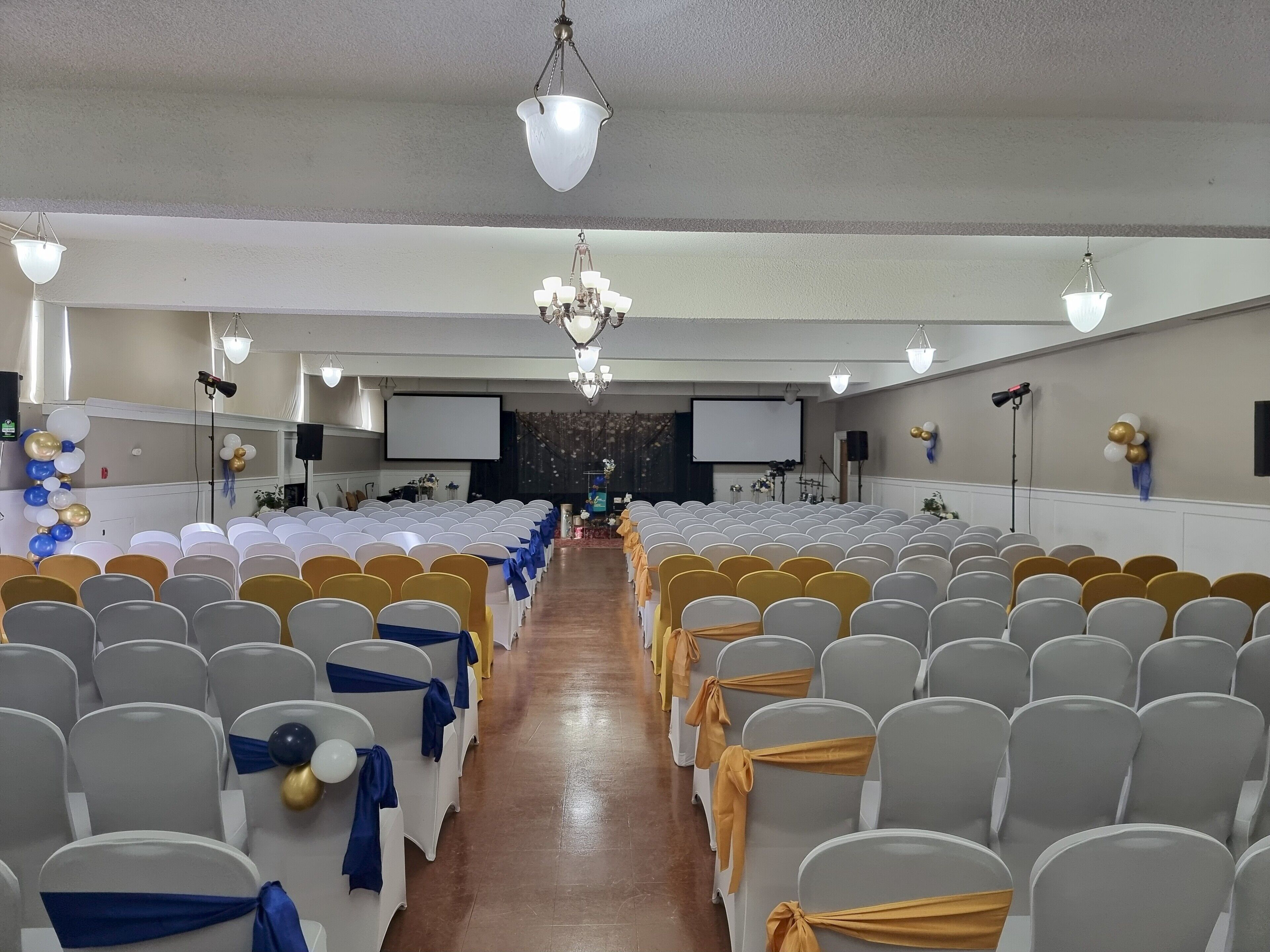 A conference room with rows of chairs, a stage, and a projector screen.