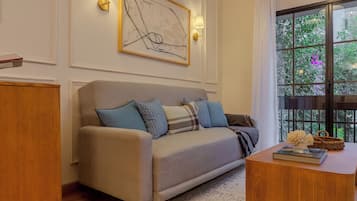 Een woonkamer met een bank, een salontafel en een raam met uitzicht op groen.