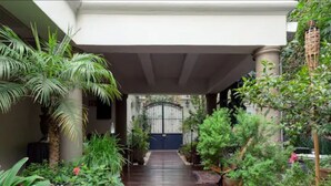 Un pasillo cubierto con plantas en macetas y una entrada con portón.