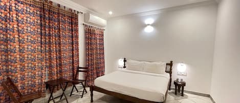 A bedroom with a bed, a chair, a table, and a ceiling fan.