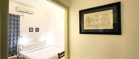 Un dormitorio con cama, una mesita y un cuadro en la pared.