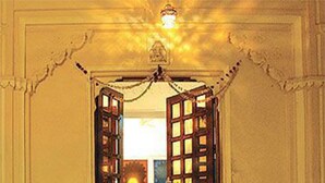 An open doorway with a chandelier above, leading to a room with a visible window and a door. - Jaiwana Haveli (Udaipur)