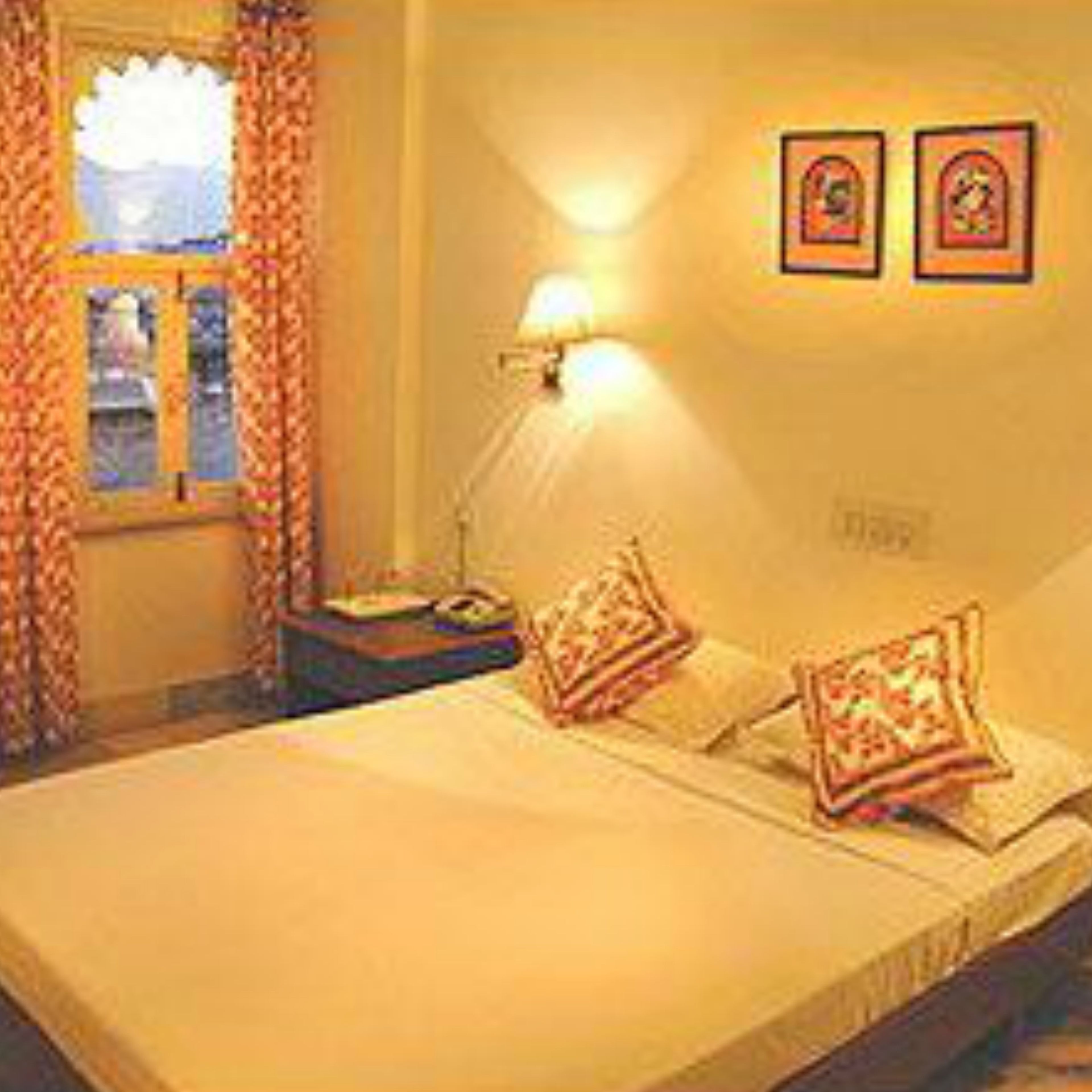 A hotel room with a bed, curtains, a nightstand, and a wall-mounted lamp.