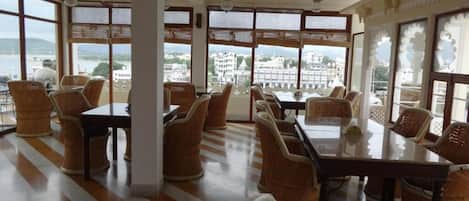 A spacious dining area with wicker furniture and large windows offering a view of the city.