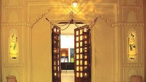 A corridor with open wooden doors leading to a room. - Jaiwana Haveli (Udaipur)