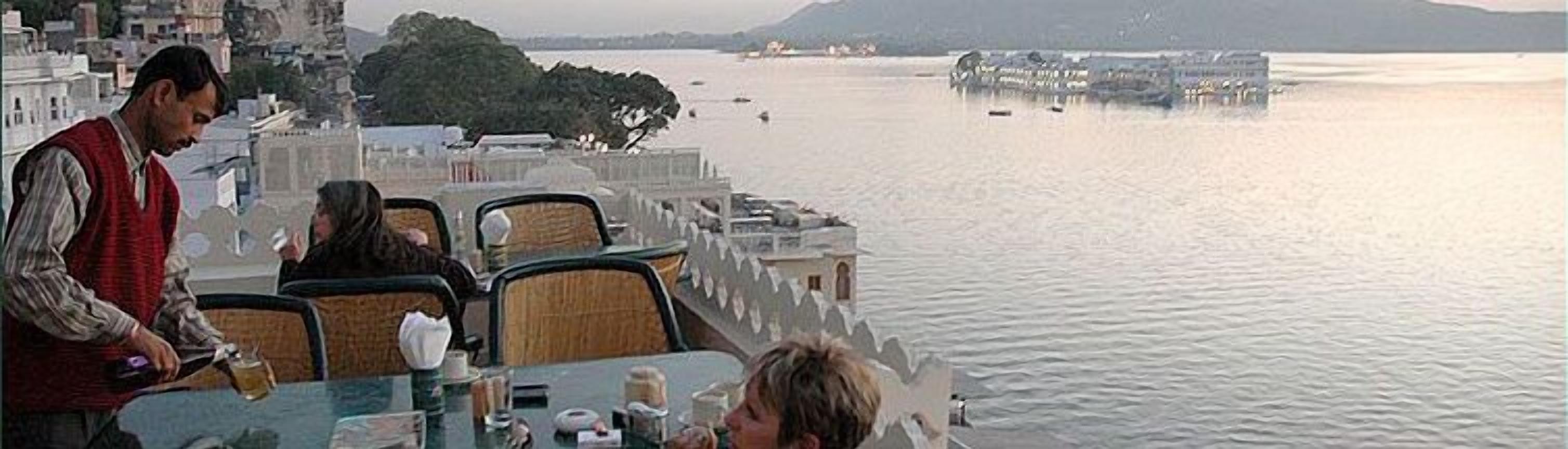 Un bote con mesa y sillas frente a un cuerpo de agua tranquilo.