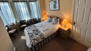 A hotel room with a bed, bedside tables, a chair, a desk, and a window with curtains. - Belvedere Guest House, Great Yarmouth (Great Yarmouth)