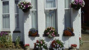 A building with multiple windows, some with hanging flower baskets. - Belvedere Guest House, Great Yarmouth (Great Yarmouth)