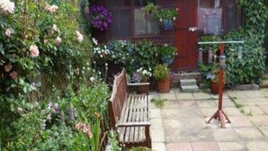 A garden with a wooden bench, potted plants, and a small table. - Belvedere Guest House, Great Yarmouth (Great Yarmouth)