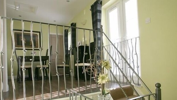A staircase with a metal railing leading to a second floor. There is a vase with flowers on the lower landing. - Blossom House Bed & Breakfast (Buxton)