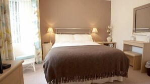 A bedroom with a bed, bedside tables, a nightstand, a dresser, and a mirror. - Blossom House Bed & Breakfast (Buxton)