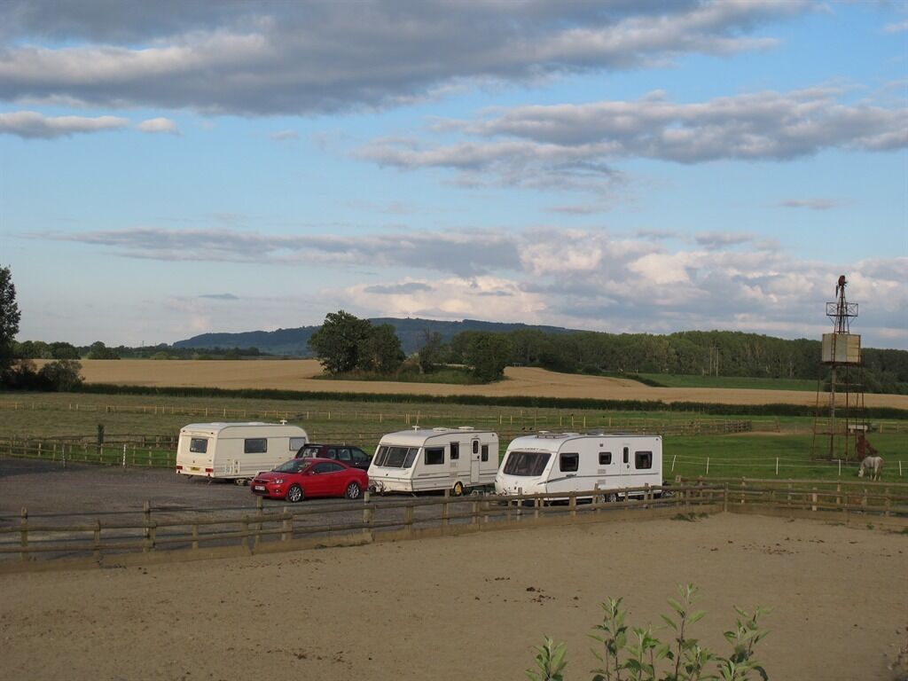 A rural campsite with RVs and a red car parked on a dirt area.