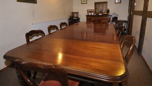 A large wooden conference table with chairs around it, a radiator, and a dresser with items on top. - Bluebell Farm (Worcester)