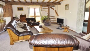 A cozy living room with leather sofas, a wooden coffee table, and a television. - Bluebell Farm (Worcester)