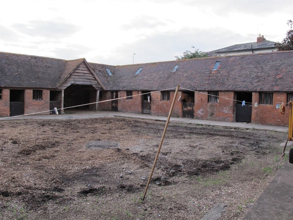 A courtyard with a brick building featuring multiple windows and a sloped roof.