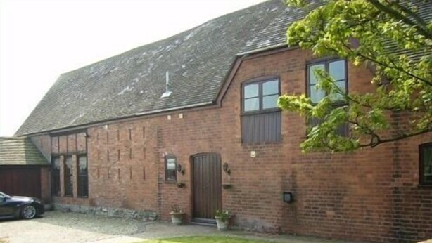 A brick building with a sloped roof, a garage, and a paved driveway. - Bluebell Farm (Worcester)