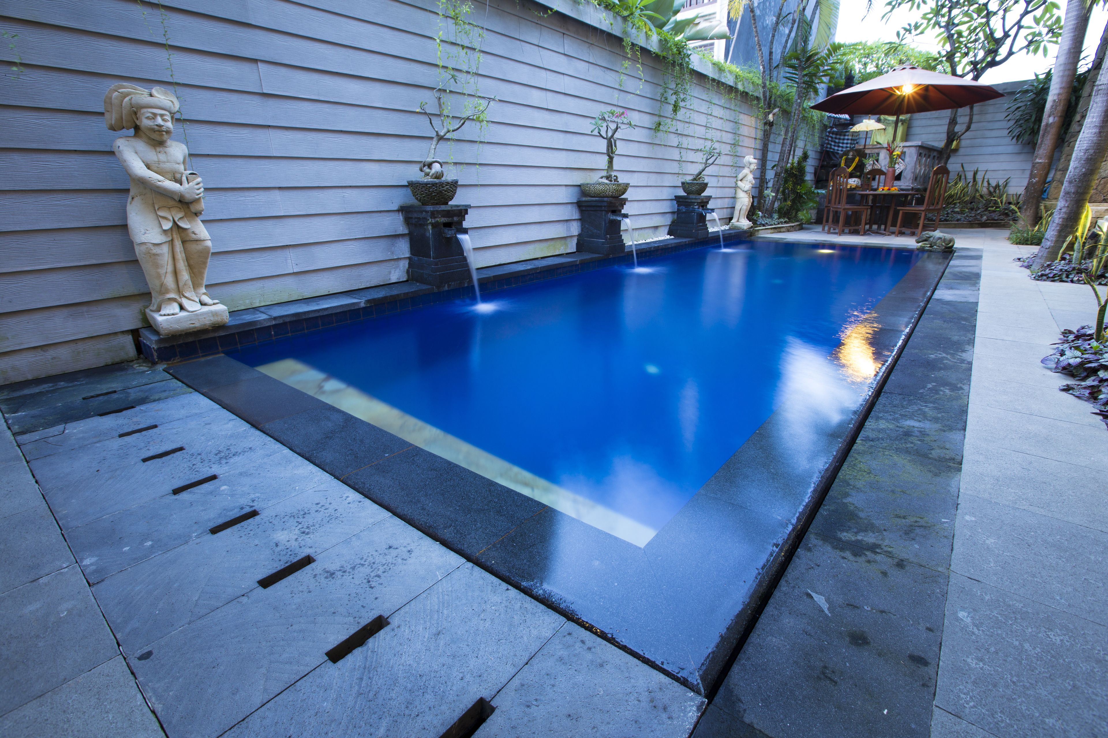 Ein Pool mit Statue, Blumentöpfen und einer Terrassenanlage.
