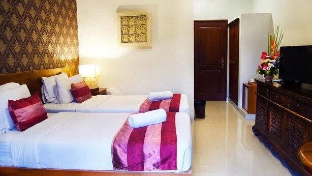 A hotel room with two beds, a TV, a wooden cabinet, and a patterned wall. - Sindhu Mertha Sanur (Denpasar)