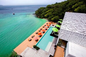 Una piscina al aire libre, sombrillas, sillones reclinables de piscina