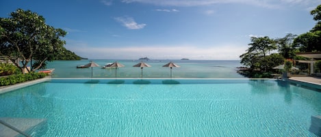 Una piscina azul cristalina con vistas al mar y a islas lejanas.