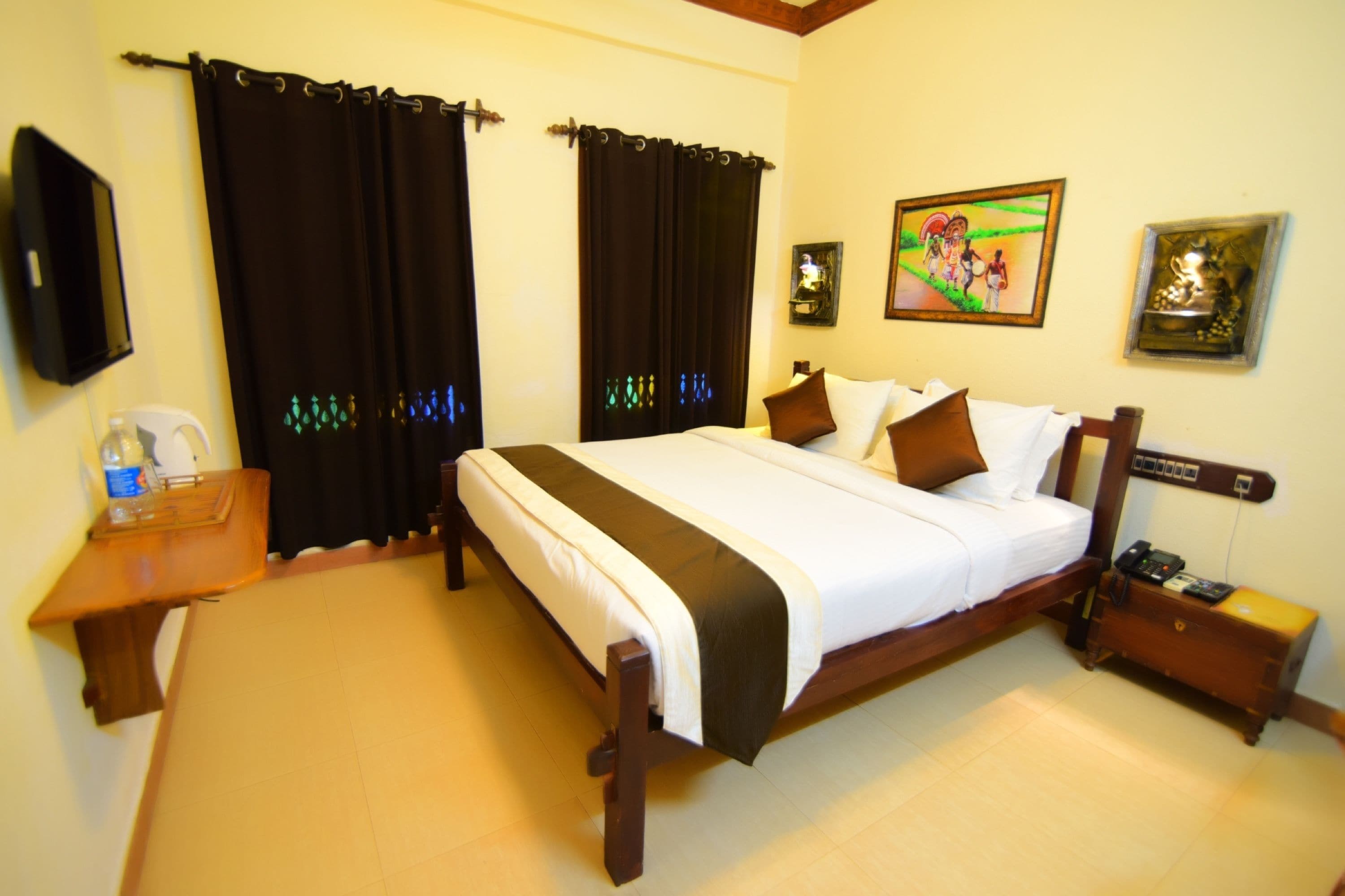 A hotel room with a bed, a bedside table, a nightstand, a wall-mounted TV, and a painting.