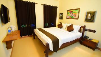 A hotel room with a bed, a bedside table, a nightstand, a wall-mounted TV, and a painting.