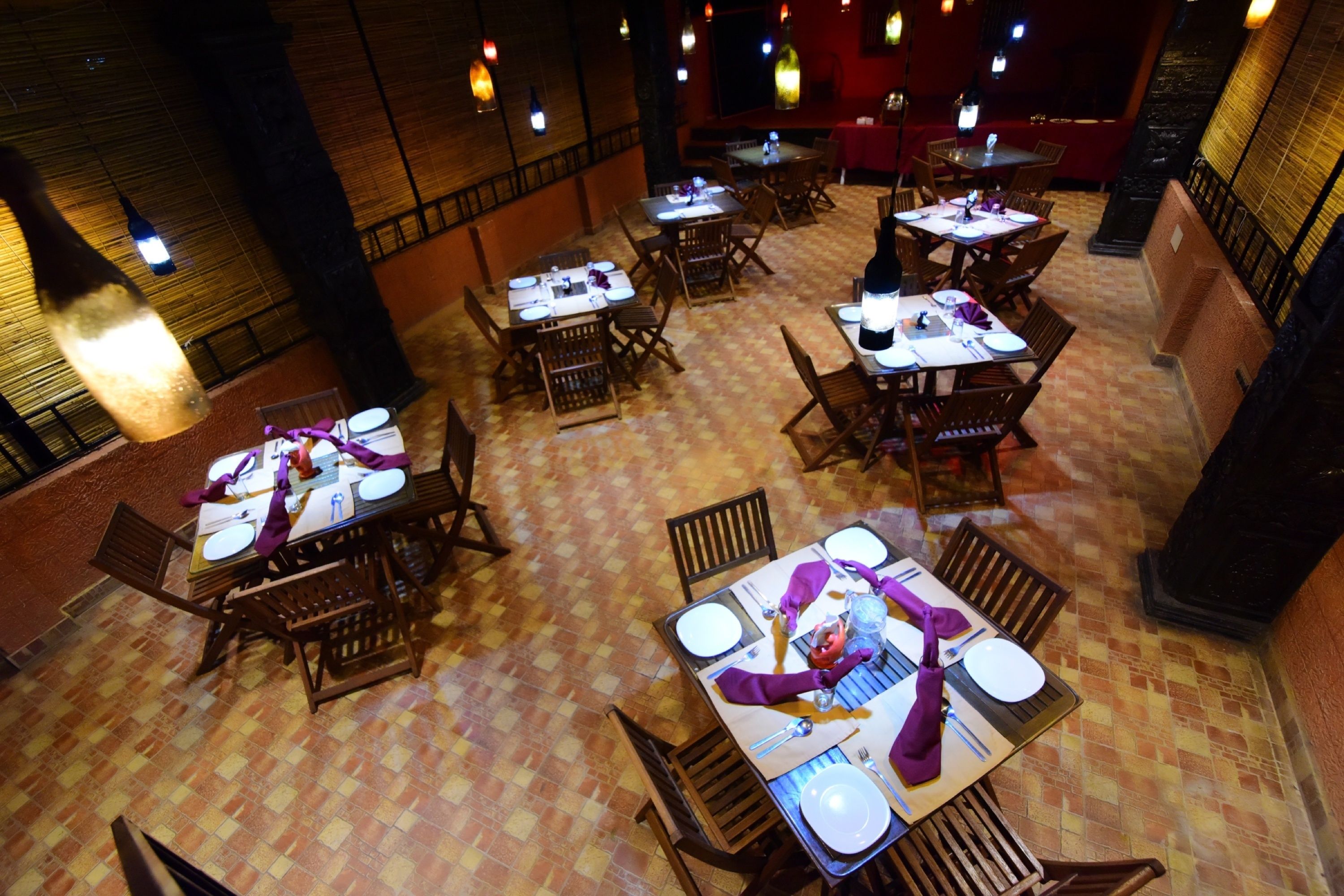 A restaurant with multiple tables set for dining, featuring a patterned floor and wooden furniture.