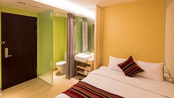 A modern hotel room with a bed, a bathroom, and a green wall.