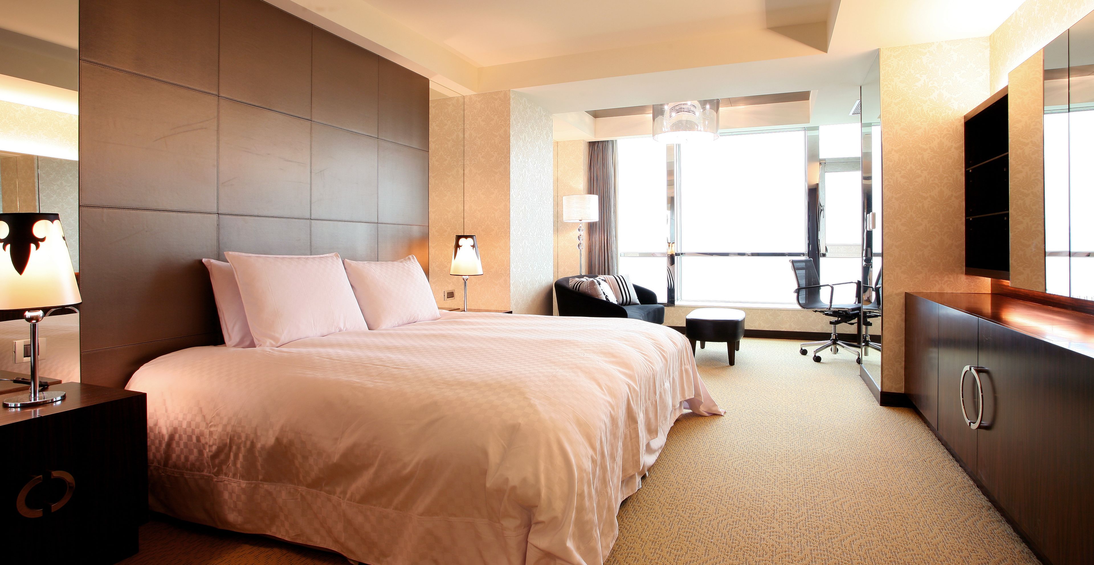 Una habitación de hotel con una cama grande, un escritorio, una silla y un televisor.