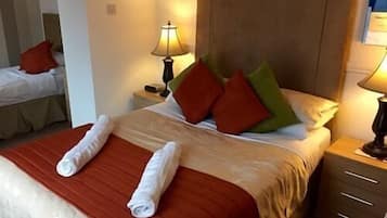 A hotel room with a neatly made bed, two bedside tables with lamps, and a wooden headboard.