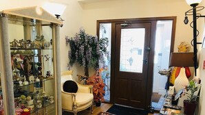 A room with a glass display cabinet filled with various items, a chair, a large potted plant, and a patterned rug. - Pelham Lodge (Blackpool)