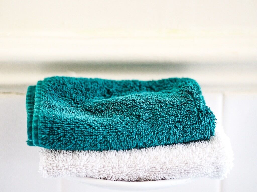 A folded teal towel on a white surface.