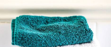 A folded teal towel on a white surface.