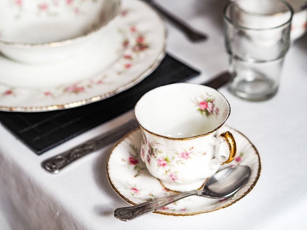 Une table dressée avec une tasse et une soucoupe à motifs floraux, une cuillère et un verre.