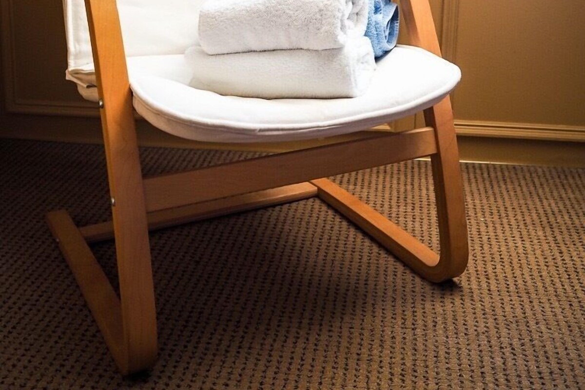 Une chaise en bois avec un coussin blanc et une serviette pliée.