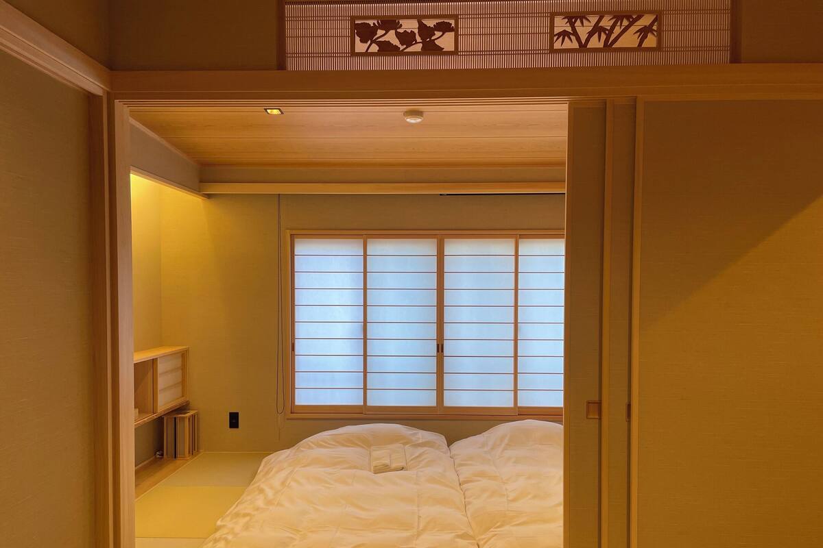A traditional Japanese-style bedroom with a futon bed, sliding shoji doors, and a tatami mat floor.