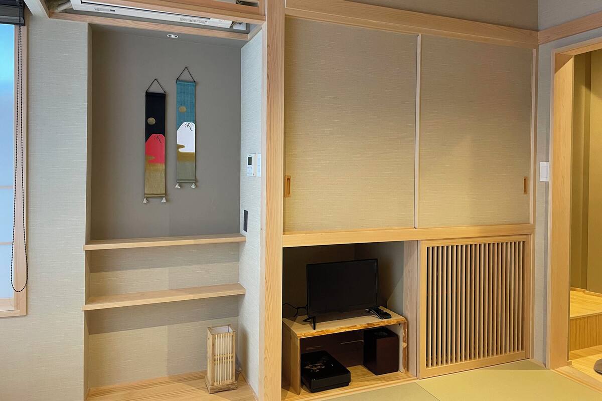 A modern room with a built-in TV, wooden shelving, and a sliding door closet.